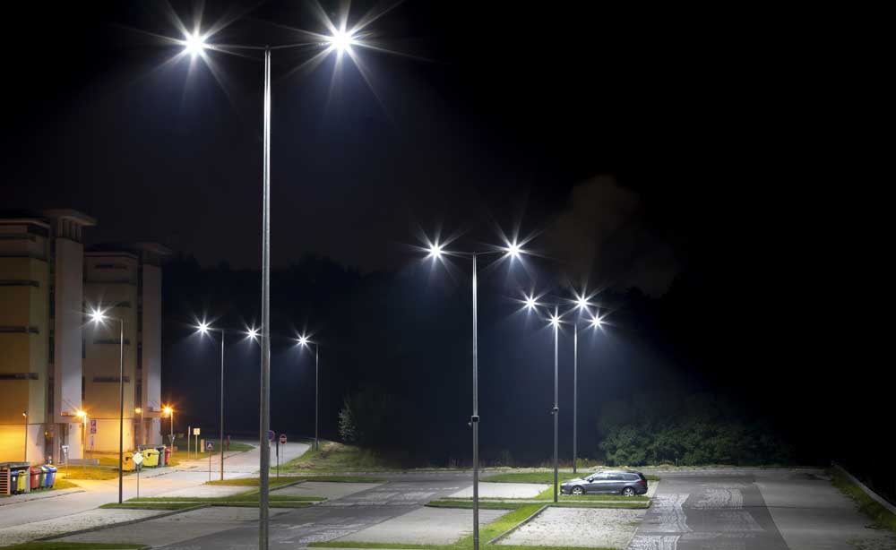 Large parking lot with larger bright lighting on poles.